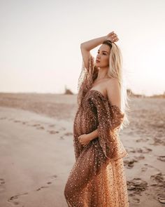 a woman standing on top of a sandy beach next to the ocean wearing a dress