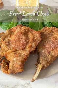 fried lamb chops on a white plate with greens and lemon wedges in the background