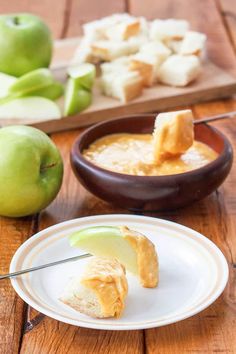 an apple is being dipped with butter on a white plate next to some green apples