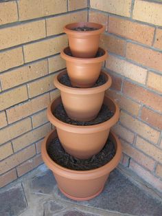 three clay pots are stacked on top of each other in front of a brick wall