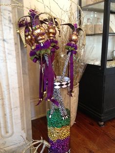 a tall vase filled with lots of different colored beads and decorations on top of a wooden floor