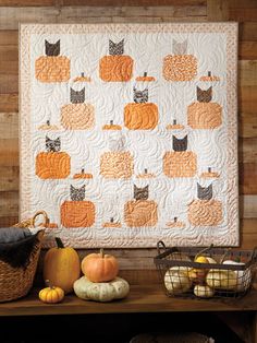 a quilted wall hanging with pumpkins and cats on it