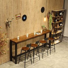 a long table with four stools next to it in front of a wooden wall