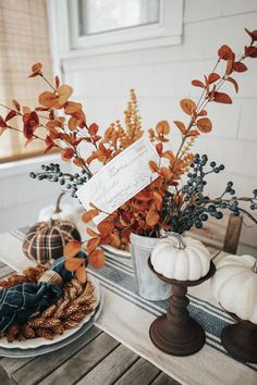 a table topped with plates and vases filled with autumn flowers next to pumpkins