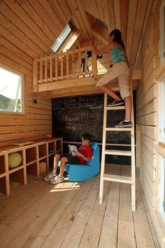 two children are playing on a loft bed in a small room with wooden walls and flooring