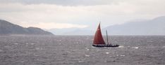 a sailboat in the middle of an ocean with mountains in the backgroud