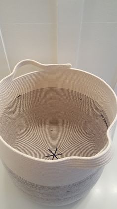 a large white basket sitting on top of a table next to a wall and floor