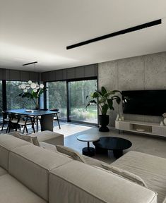 a living room with couches and tables in front of large glass doors that look out onto the outdoors