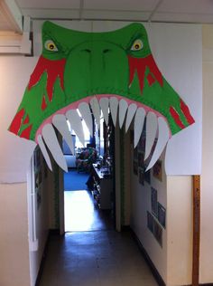 a large green and red alligator head hanging from the side of a wall in a hallway