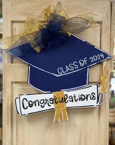 a blue graduation cap with gold ribbon and congratulations stickers attached to the front door