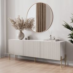 a white sideboard with a mirror and plants