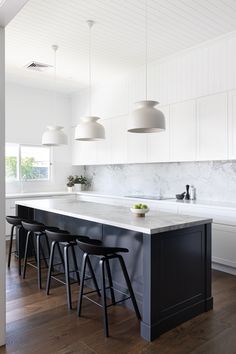 a kitchen with marble counter tops and stools in front of the island that has four black barstools