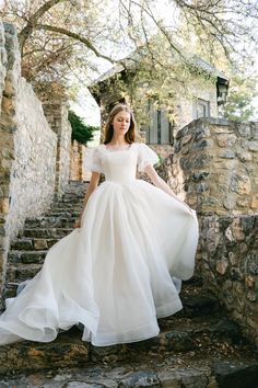 a woman in a white dress is walking down some stairs