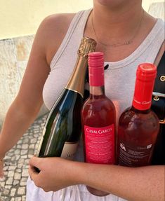 a woman holding three bottles of wine in her hands