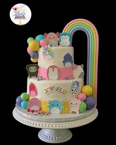 there is a multi layer cake decorated with animals and rainbows on the top tier