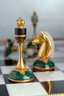 two gold and green chess pieces on a black and white checkered board