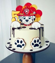 a birthday cake decorated with paw prints and a fireman's hat on top