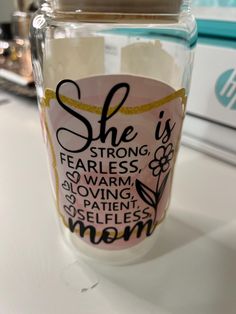 there is a glass jar with some writing on the lid and it says she is strong, fearless, warm, loving, patient