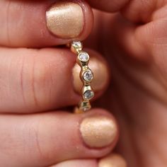 a woman's hand holding a gold ring with diamonds