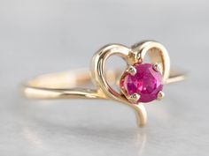 "A simple and romantic ruby ring perfect for everyday wear! A polished open heart decorates the center of this piece, while four sturdy prongs frame and protect the stone. Metal: 14K Yellow Gold Gem: Ruby Gem Measurements: 3.7 mm, Round Ring Size: 6.50 Marks: \"+14K\" Stamped on the inside band SKU #: 6R58QJCR Each piece has been identified and graded by a Graduate Gemologist who has been certified by the Gemological Institute of America (GIA). We have five brick and mortar storefronts in Maine, Gold Ruby Ring, Yellow Gold Sapphire Ring, Gem Ruby, Ruby Ring Gold, Gold Heart Ring, Cameo Ring, Round Rings, July Birthstone, Open Heart