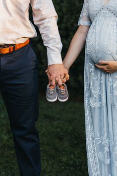 a pregnant couple holding hands while standing next to each other