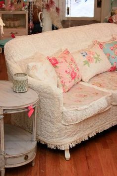 a white couch sitting next to a small table on top of a hard wood floor