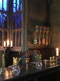 a long table with candles on it in front of a stained glass window at night