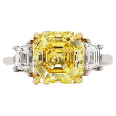 From SCARSELLI, this beautiful statement ring features a 3 carat Fancy Vivid Yellow Emerald Cut Diamond flanked by a couple of E color VS clarity trapezoid cut white diamonds totaling 0.72 carats (see GIA certificate picture for more detailed center stone information) This ring can be size or the center diamond re-designed with Scarselli to suit the client's specifications. Should a client wish to customize settings to personalize the look, such as changing side stones or bands, we are happy to Square Cut Diamond Ring, Canary Diamond Ring, Square Cut Rings, Radiant Diamond Rings, Canary Diamond, Emerald Cut Diamond Ring, Yellow Diamond Rings, Moissanite Diamond Rings, Emerald Cut Diamond