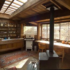 an old fashioned kitchen with wood stove and wooden shelves on the wall, along with lots of windows