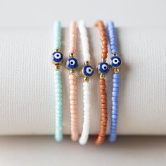 three bracelets with evil eyes on them sitting on top of a white cloth napkin