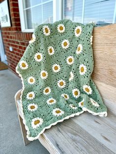 a crocheted blanket sitting on top of a wooden bench next to a window