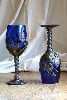 two blue glass vases sitting on top of a wooden table