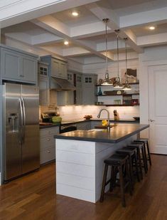 a kitchen with stainless steel appliances and wooden floors, along with an island in the middle