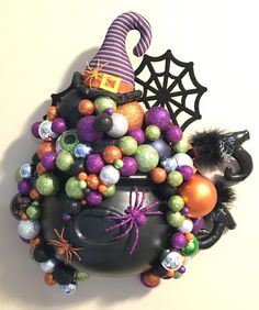 a witches caulder filled with halloween decorations on top of a white wall next to a spider web