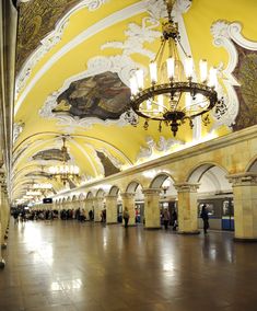 an empty train station with chandeliers hanging from the ceiling and paintings on the walls