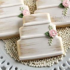 three decorated cookies sitting on top of a white plate with pink and green flowers in the middle