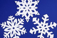 three snowflakes on a blue background are cut out from paper and placed together