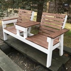 two wooden benches sitting next to each other on top of a bench in front of a tree