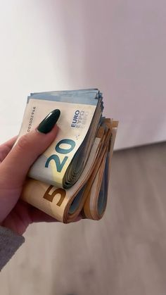 a person holding money in their hand with green nail polish on it's nails