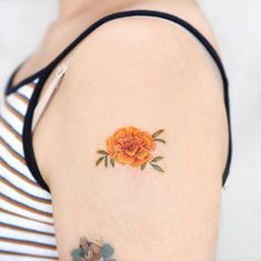 an orange flower on the back of a woman's shoulder