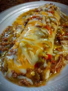 a white plate topped with meat and cheese covered enchilada