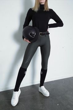 a woman is holding a helmet and posing for the camera with her hands on her hips