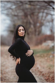 a pregnant woman poses for the camera in a black dress with her hands on her hips