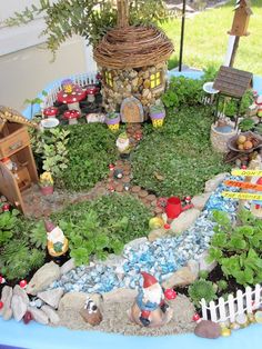 a fairy garden with gnomes and plants in the center, including rocks, grass, trees, and small houses