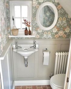 a bathroom with a toilet, sink and mirror in it's corner next to a radiator