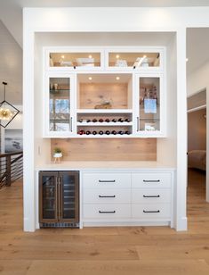 a kitchen with white cabinets and wood flooring in the center, along with a wine rack