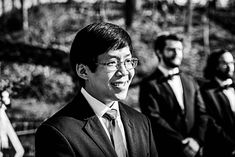 two men in suits and ties standing next to each other with trees in the background