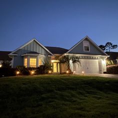 a house that is lit up at night with lights on the front and side of it