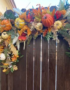 a wooden fence decorated with pumpkins, leaves and other autumn decorations on it's side