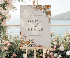 an easel with a sign that says olive and lucas on it in front of flowers